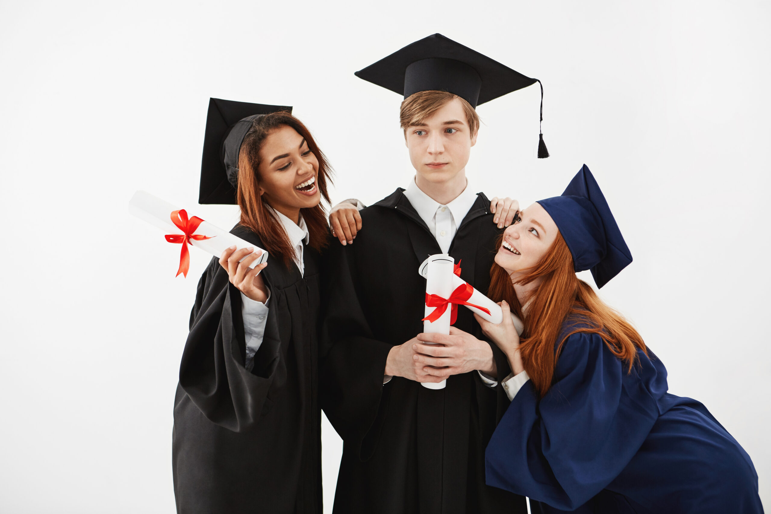 Three international students graduates rejoicing smiling posing over white background.