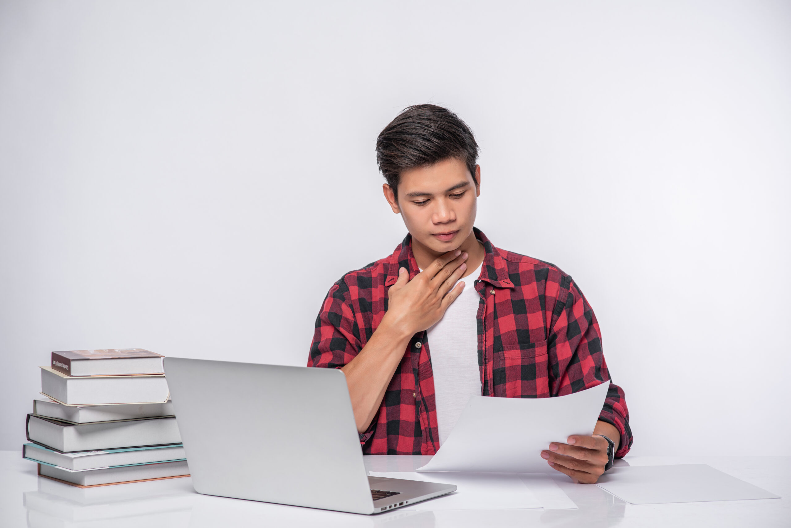 A man using a laptop in the office and doing a document analysis.